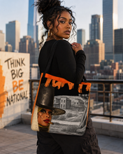 Load image into Gallery viewer, A woman stands on a rooftop terrace with a city skyline in the background, carrying a tote bag over her shoulder. The tote bag features a black and white illustration of a woman (Erykah Badu) in a cowboy hat next to an orange brushstroke graphic with the text 'TOWN'.