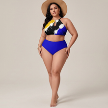 Load image into Gallery viewer, A plus-size model wearing a two-piece swimsuit with a colorful abstract print on the top and solid royal blue bottoms, styled with a wide-brimmed straw hat against a neutral beige studio background.